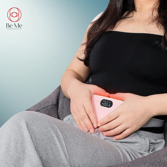A person sitting and holding a BeMe branded heating pad and electric massager on their lap.