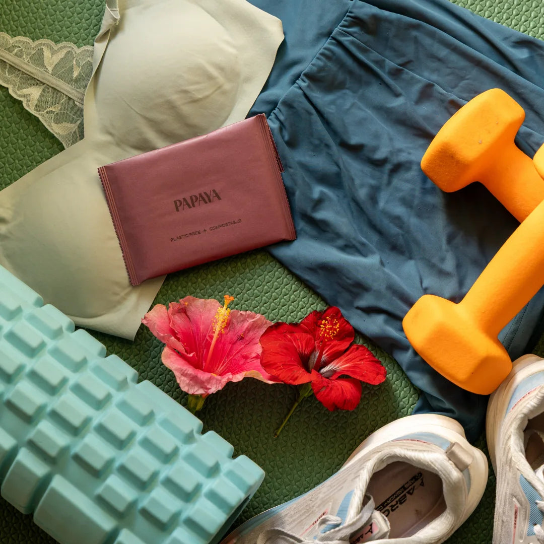 Pillow, pink pouch, dumbbells, flowers, and shoes on a green surface