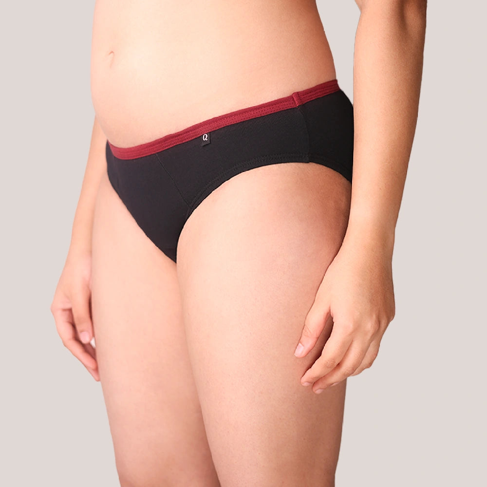 Black period underwear with red waistband on a neutral background