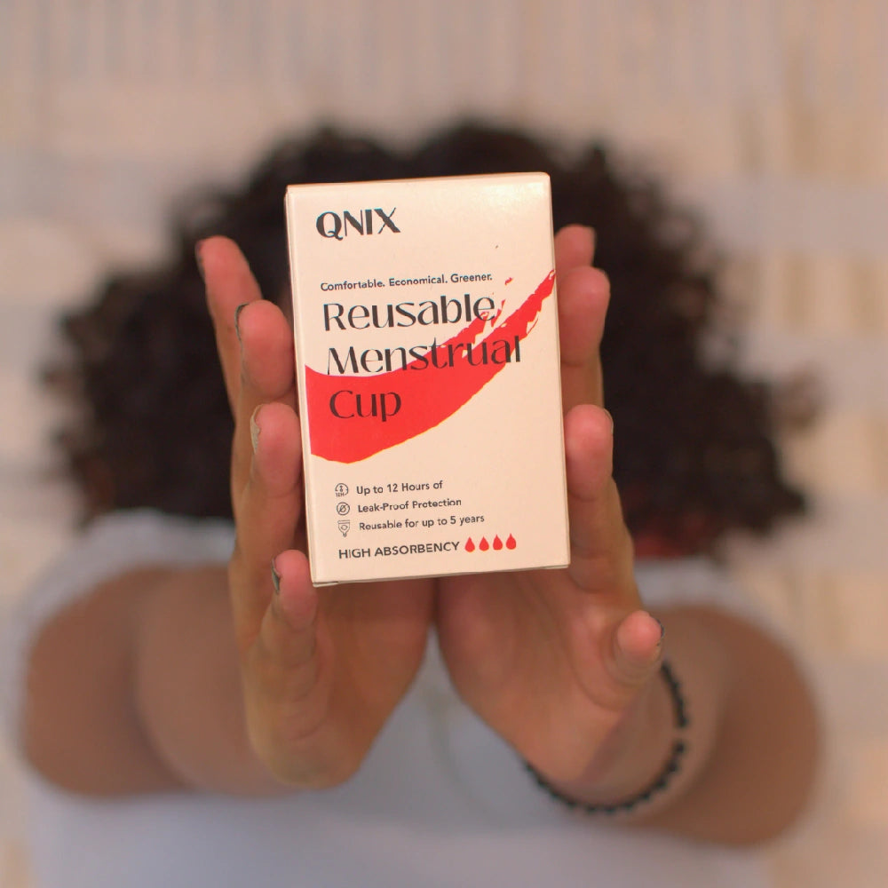 Person holding a QNIX reusable menstrual cup box with a blurred background