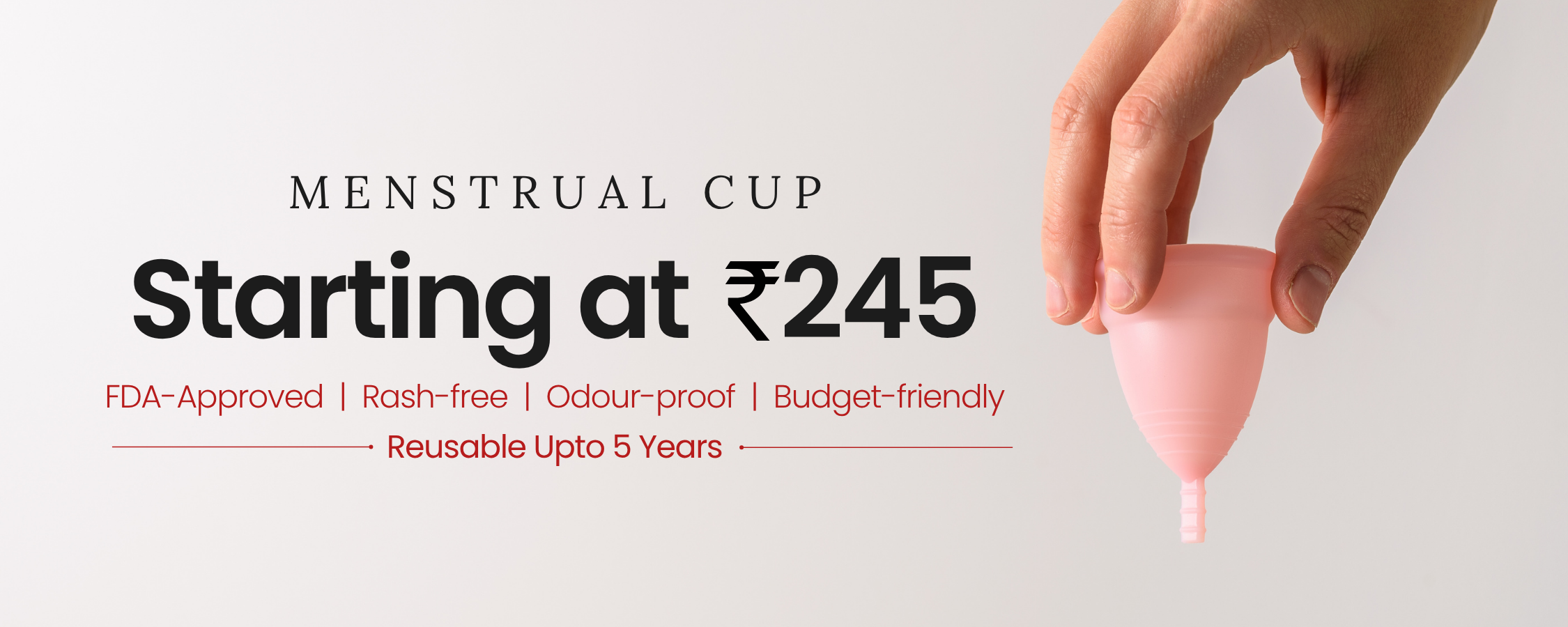 Pink menstrual cup held by a hand with promotional text on a light gray background
